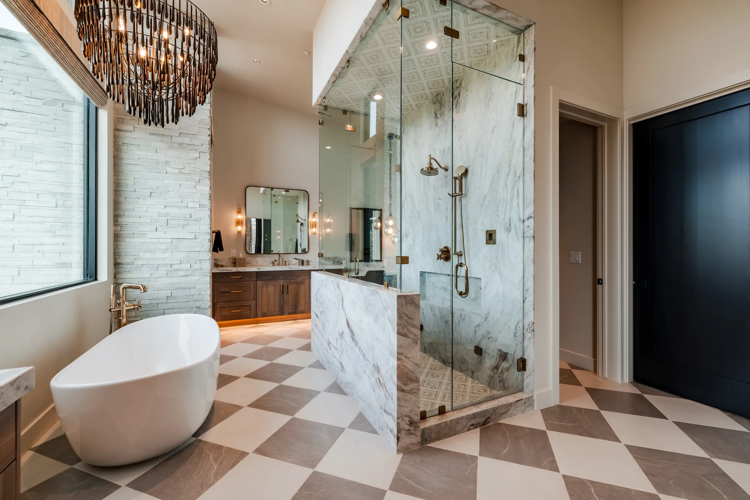 Primary bathroom in a Park City custom home with a marble shower enclosure, freestanding soaking tub, and checkerboard stone floor