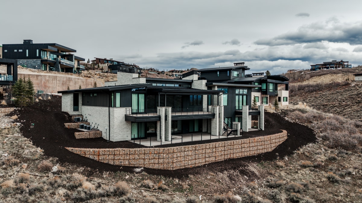 Pinnacle Lot 47 Park City Utah — rear elevation with cantilevered balconies, stone retaining walls, and hillside backdrop