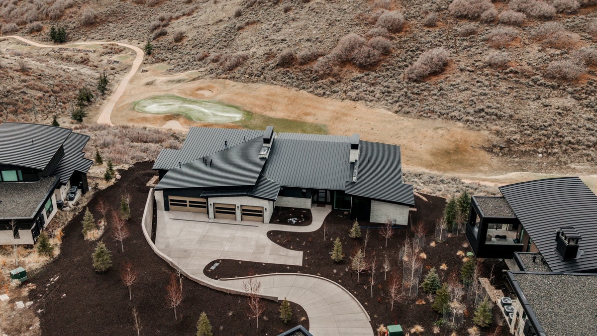 Pinnacle Lot 47 Park City Utah — bird's-eye view of standing-seam metal roof, three-car garage, and curved driveway by golf green