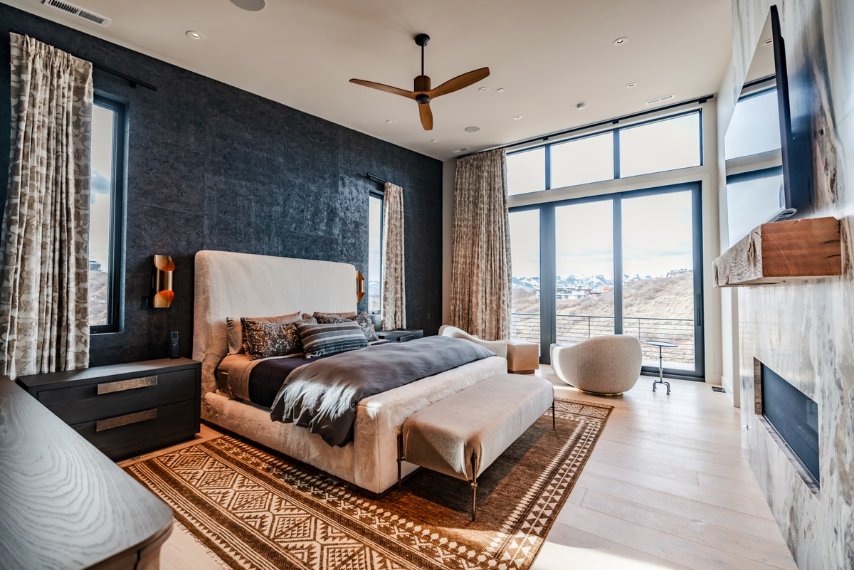Pinnacle Lot 47 Park City Utah — primary suite with marble fireplace surround and snow-capped mountain views through floor-to-ceiling windows