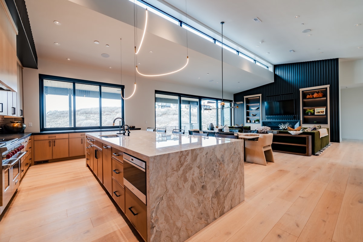 Pinnacle Lot 47 Park City Utah — great room and chef's kitchen with waterfall quartzite island, sculpted pendants, and mountain views