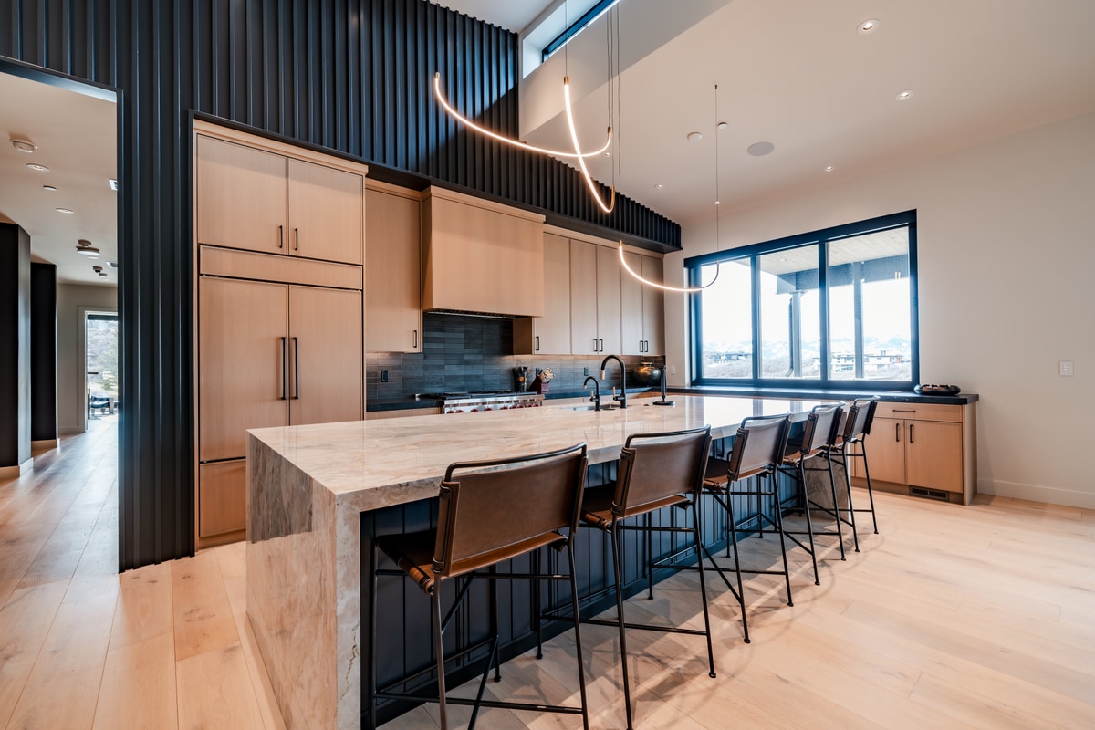 Pinnacle Lot 47 Park City Utah — kitchen with book-matched quartzite island, leather barstools, and curvilinear pendant fixtures