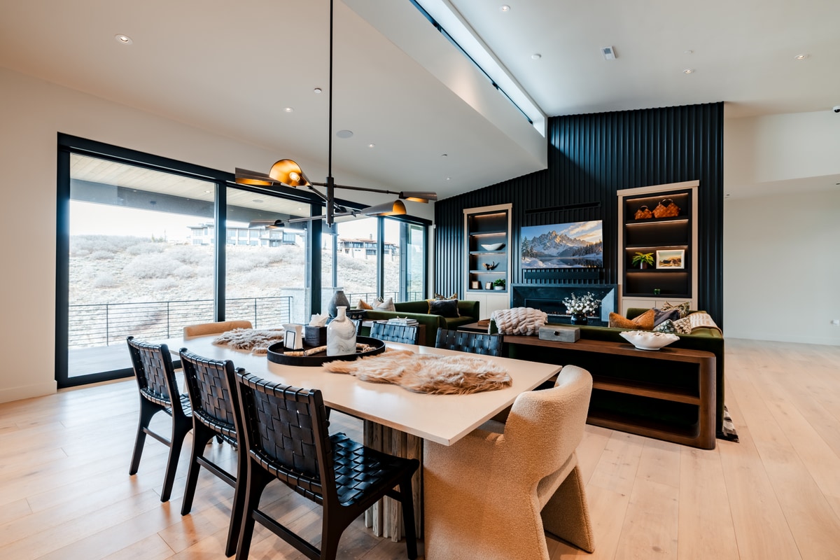 Pinnacle Lot 47 Park City Utah — open-plan dining area with woven leather chairs, brass pendants, and hillside sightlines