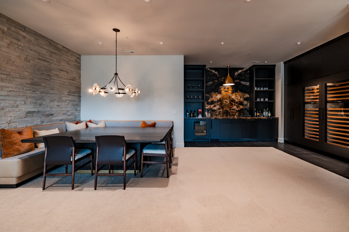 Pinnacle Lot 47 Park City Utah — bar and game lounge with blue cabinetry, stone feature wall, and illuminated wine storage