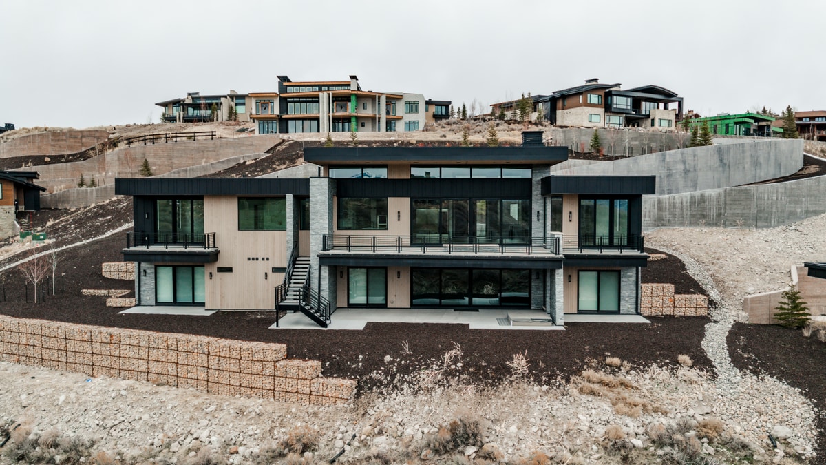 Pinnacle Lot 49 Park City Utah — rear elevation with cantilevered decks, floor-to-ceiling glazing, and stacked stone cladding