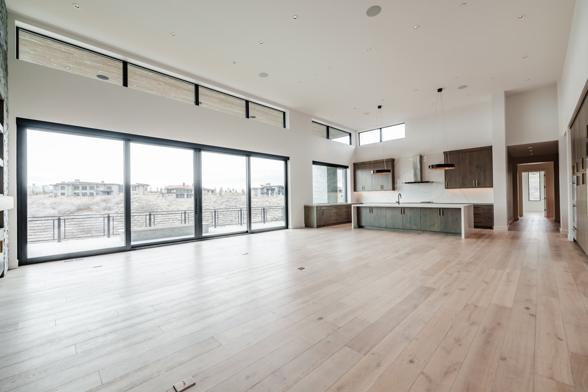 Pinnacle Lot 49 Park City Utah — expansive great room with white oak floors, floor-to-ceiling sliding glass walls, and open kitchen