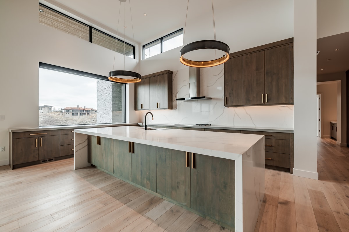 Pinnacle Lot 49 Park City Utah — kitchen with sage green island cabinetry, book-matched quartz backsplash, and clerestory windows