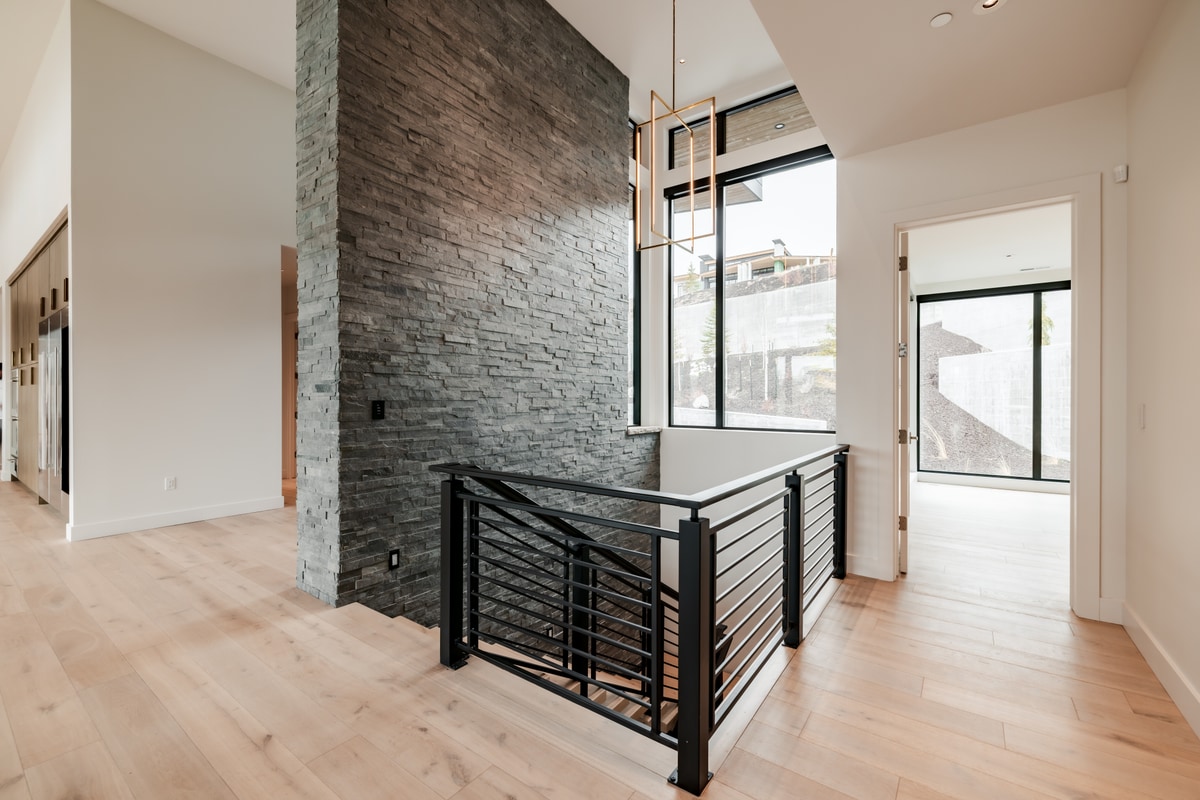 Pinnacle Lot 49 Park City Utah — upper landing with ledger stone feature wall, linear chandelier, and steel horizontal railing