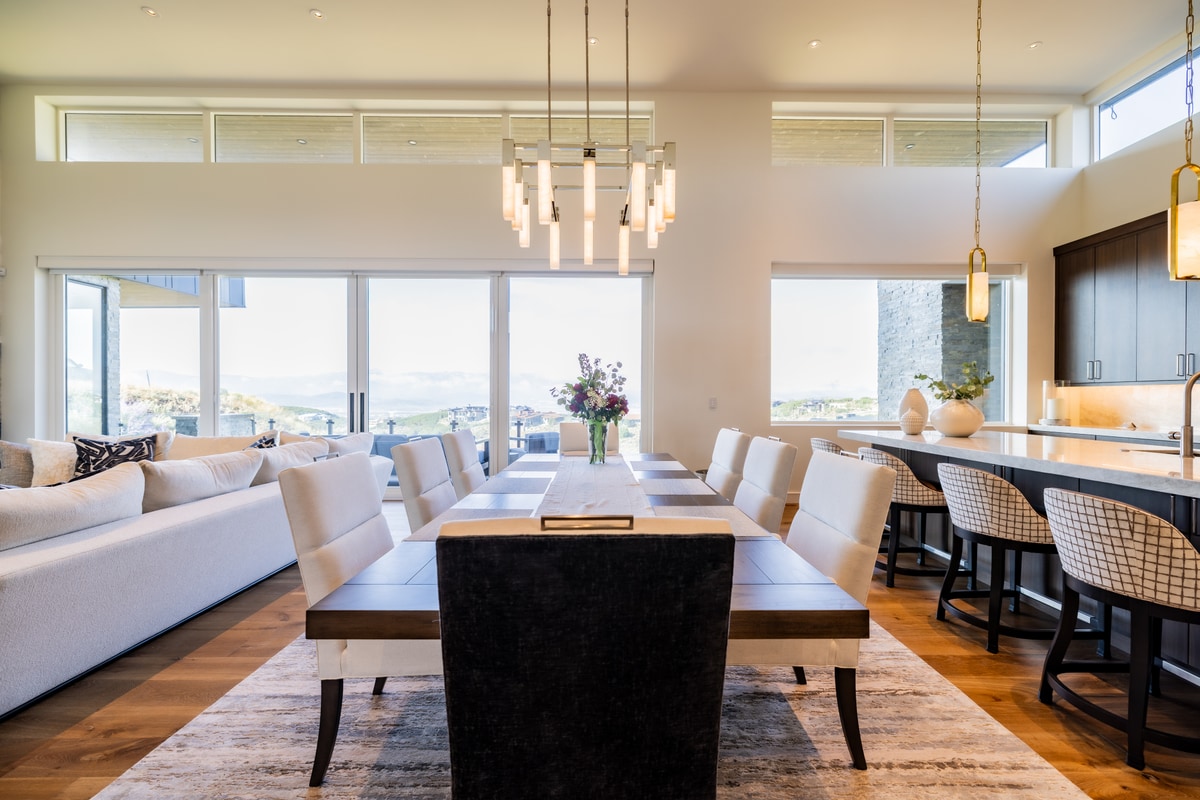 Promontory Lot 52 Park City Utah — open-plan dining room with linear chandelier, ten-seat table, and golf course views