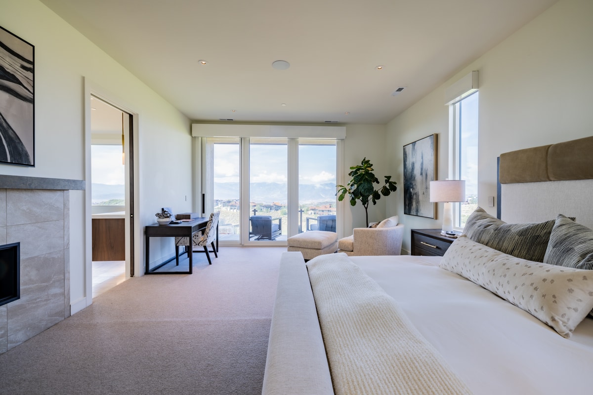 Promontory Lot 52 Park City Utah — primary suite with slab fireplace, private balcony, sitting area, and sweeping mountain views