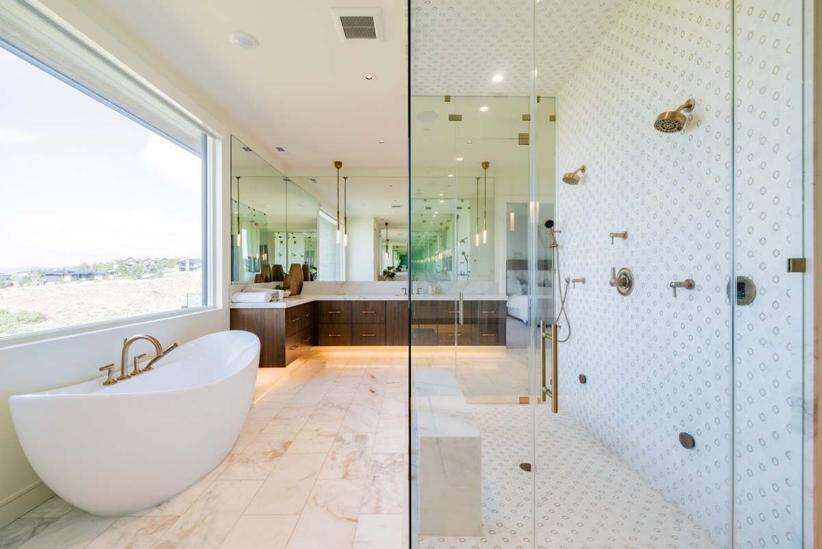 Promontory Lot 52 Park City Utah — primary bath with freestanding soaking tub, brass fixtures, marble flooring, and steam shower