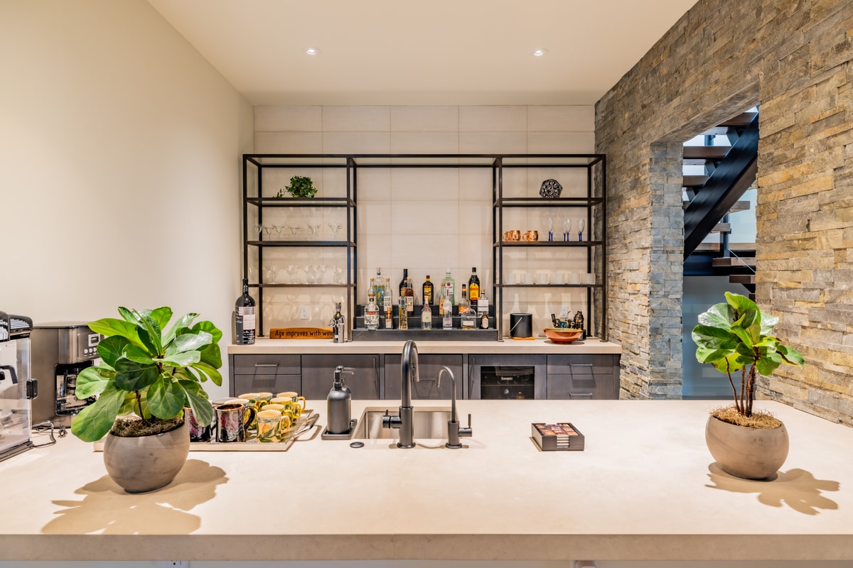 Promontory Lot 52 Park City Utah — lower-level wet bar with steel shelving, beverage center, and stacked-stone accent wall
