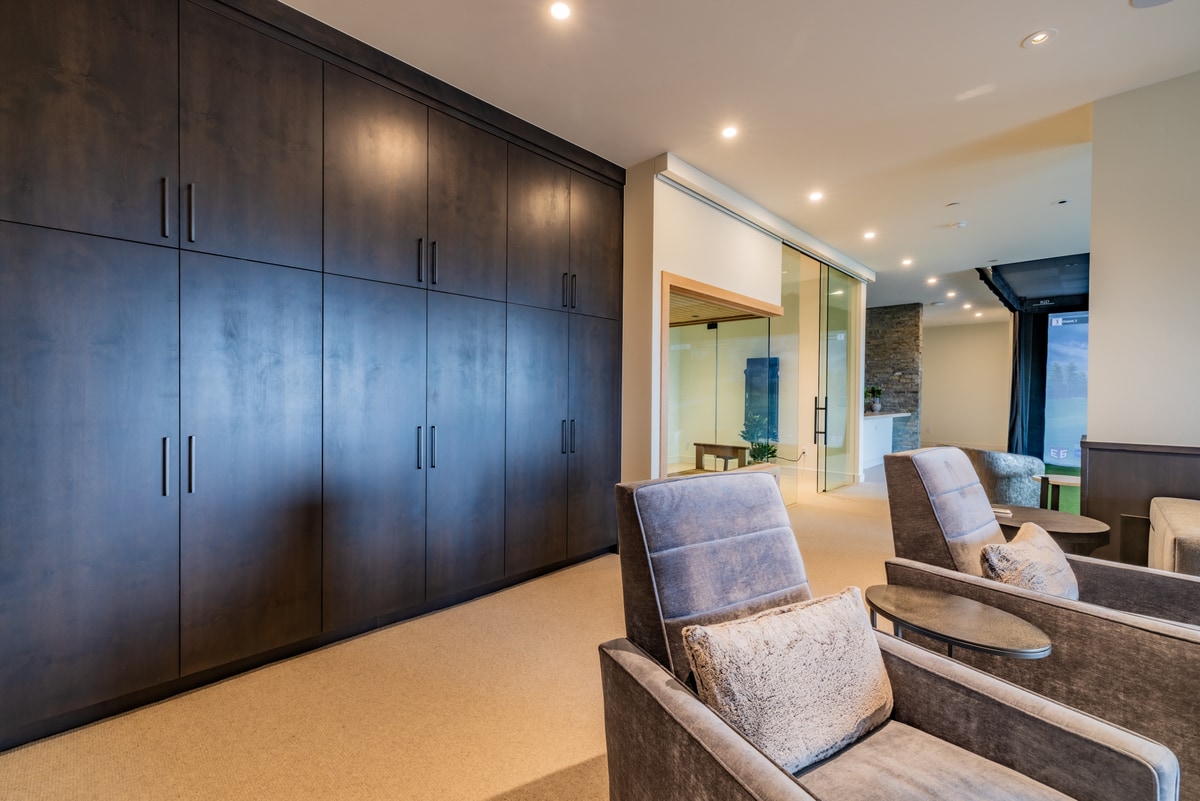 Promontory Lot 52 Park City Utah — lower-level lounge with dark cabinetry wall, plush theater seating, and wellness space views