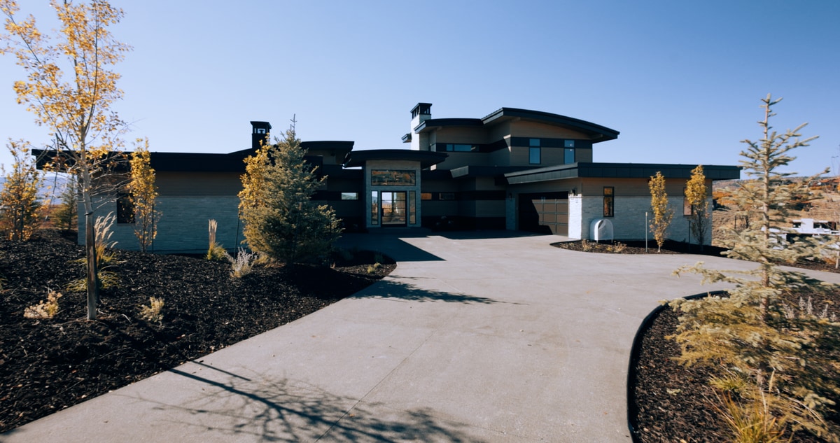 Promontory Model Home Park City Utah — front elevation approach with dark contemporary cladding, concrete driveway, and autumn aspen landscaping