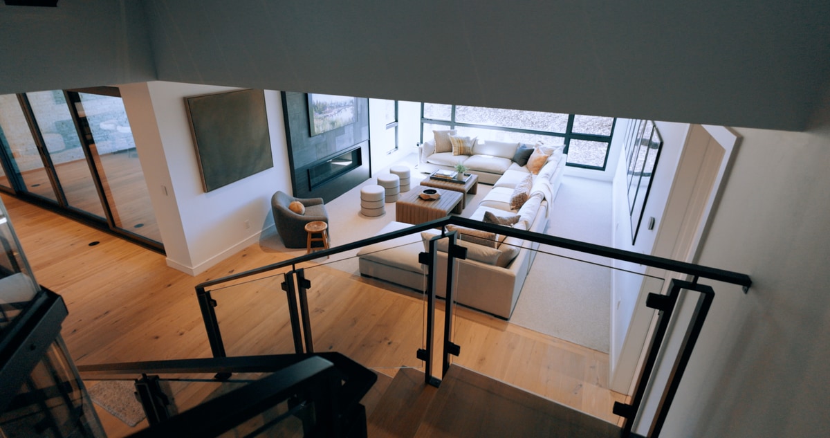 Promontory Model Home Park City Utah — upper landing overlook with steel-and-glass railing, white oak flooring, and sightline to lower living area