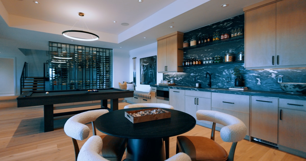 Promontory Model Home Park City Utah — lower-level entertainment area with dark marble wet bar, billiard table, glass wine wall, and ring chandelier