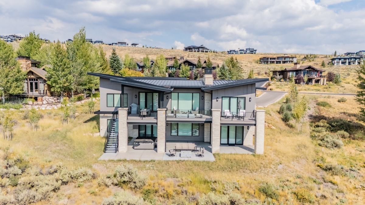 Ranch Gardens Park City Utah — rear elevation with tiered covered decks, floor-to-ceiling glazing, and high-desert mountain views