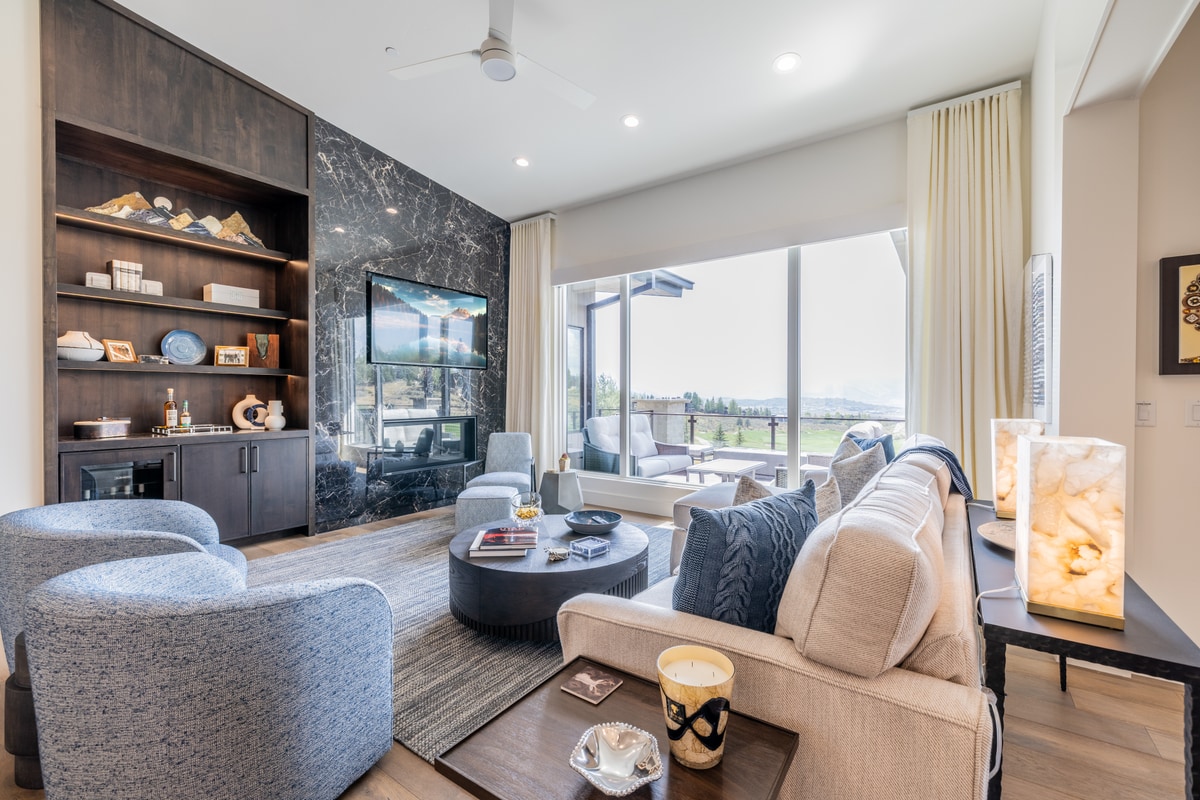 Ranch Gardens Park City Utah — media lounge with book-matched dark marble fireplace, custom walnut built-ins, and sliding glass doors