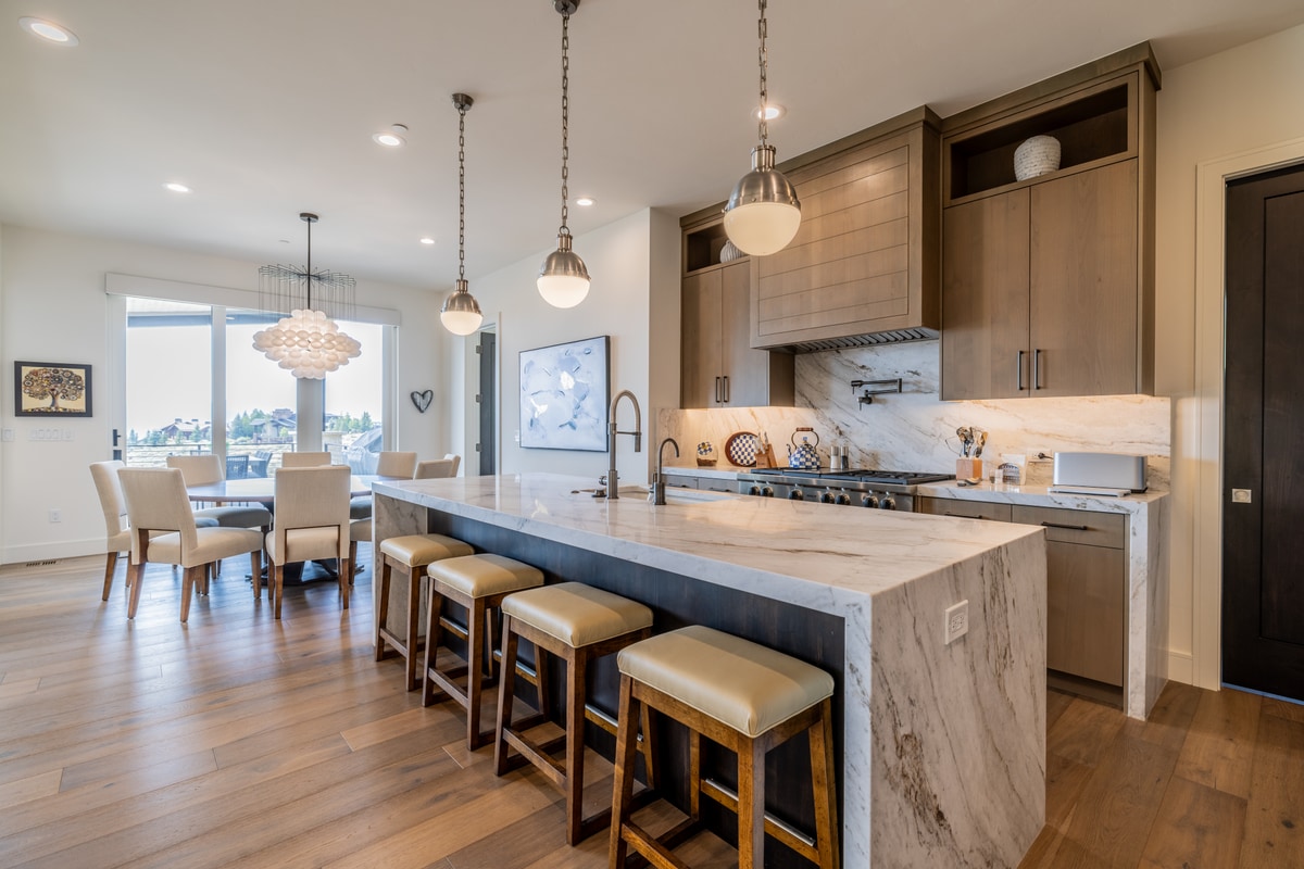 Ranch Gardens Park City Utah — chef's kitchen with quartzite waterfall island, globe pendants, taupe cabinetry, and professional range