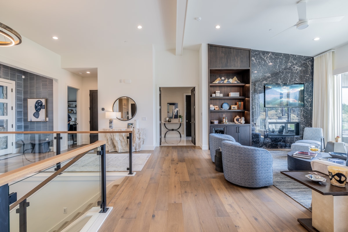 Ranch Gardens Park City Utah — upper-level hallway landing with wood-and-glass stair railing and sightline into media and living areas