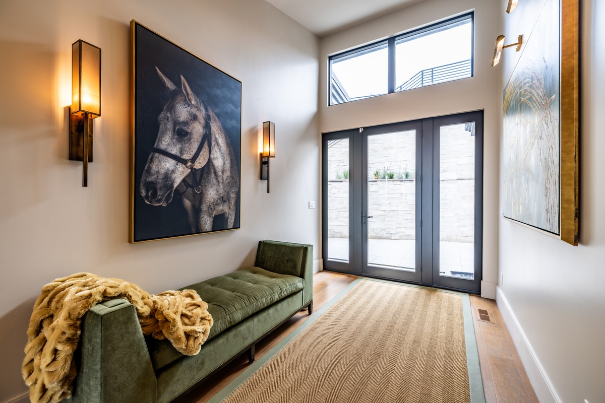 Summit Estates Park City Utah — foyer sitting area with double-height ceiling, French doors, tufted velvet daybed, and equestrian portrait