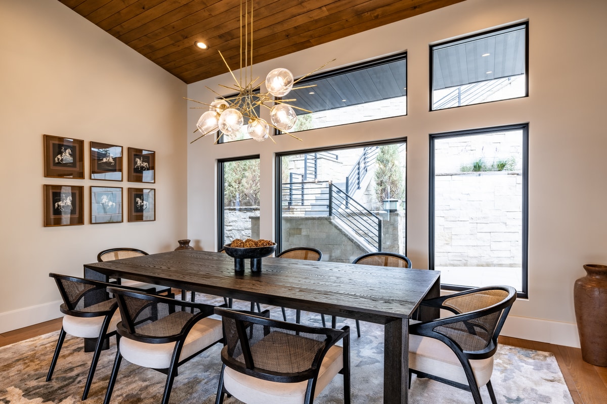 Summit Estates Park City Utah — dining room detail with sputnik-style brass chandelier, woven-back chairs, and wood plank ceiling