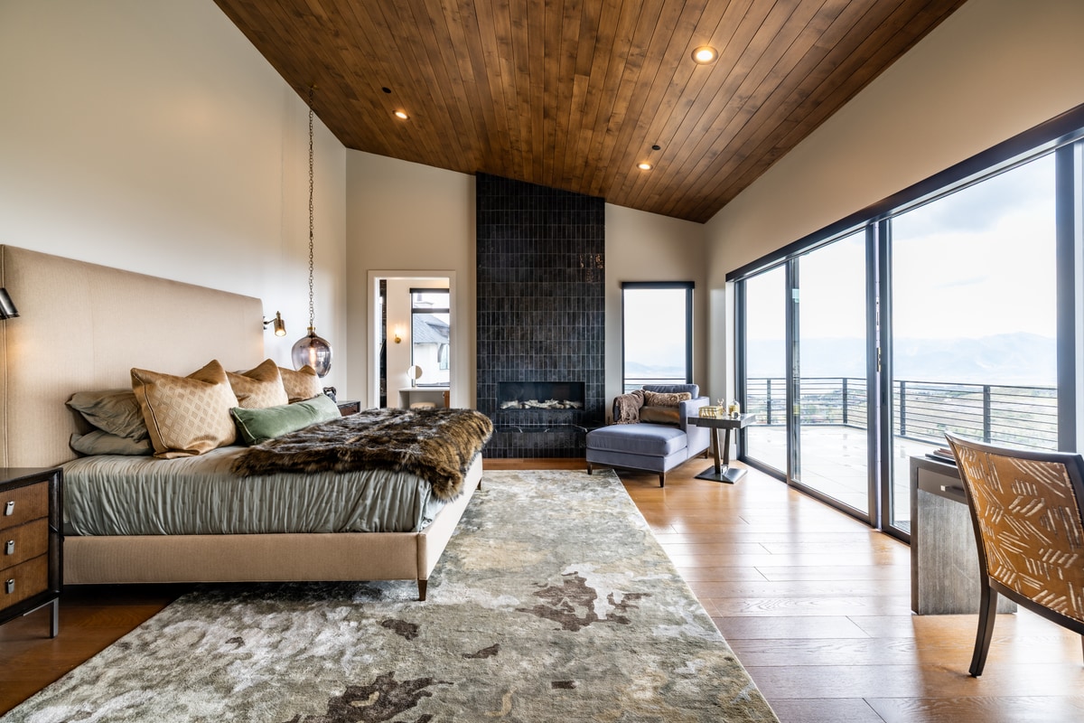 Summit Estates Park City Utah — primary suite with vaulted wood ceiling, fireplace surround, and glass doors to private mountain-view deck