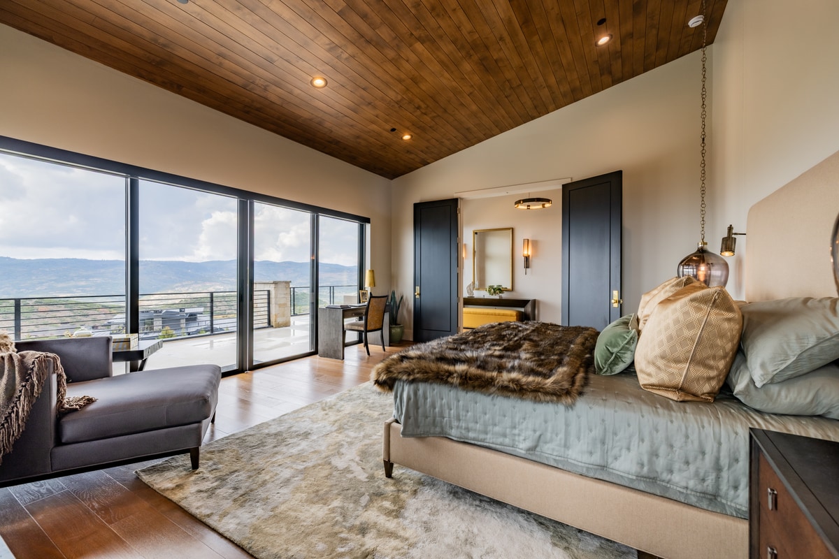 Summit Estates Park City Utah — primary bedroom with pitched wood ceiling, sliding glass doors, and panoramic Wasatch Mountain views