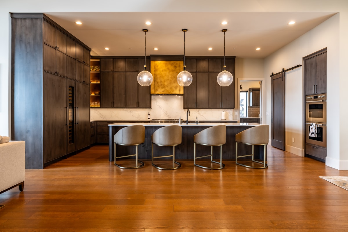 Summit Estates Park City Utah — chef's kitchen with espresso cabinetry, gold metallic range hood, waterfall island, and globe pendants