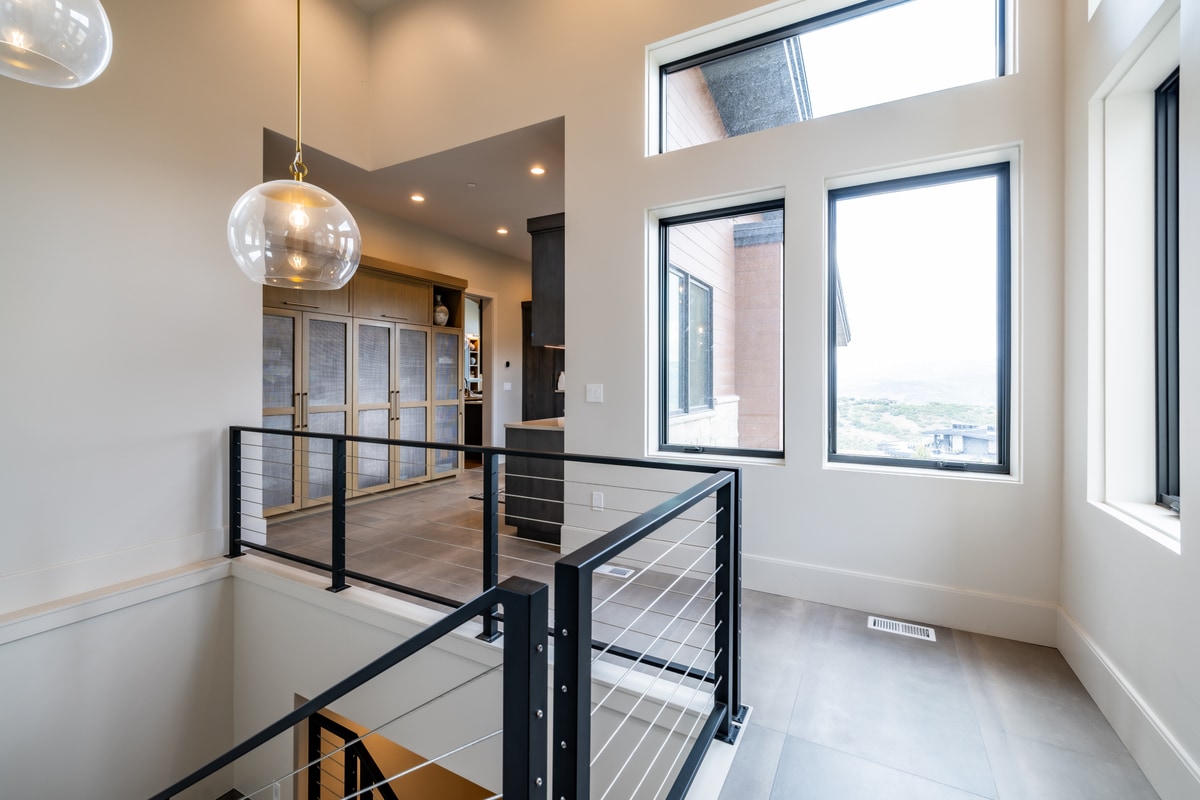 Summit Estates Park City Utah — upper landing with cable-railing staircase, globe pendant light, and clerestory windows