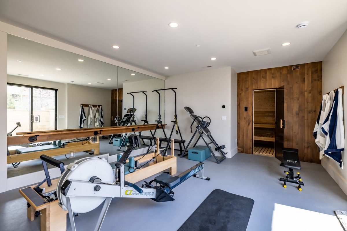 Summit Estates Park City Utah — private fitness studio with Pilates reformer, mirror wall, and cedar-door sauna room